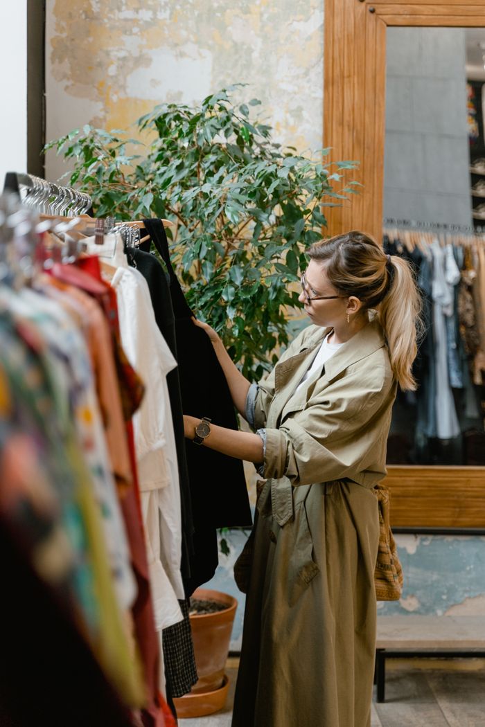 Stylish woman browsing clothing rack in store, showcasing modern fashion trends.
